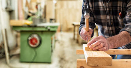 Close-up. Carpenter with hammer and nails fixes a wooden board. Construction industry, do it yourself. の写真素材