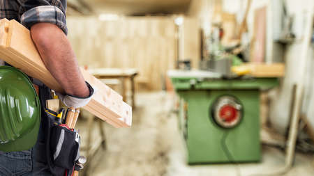 Close-up. Carpenter with his hands protected by gloves carries the wooden boards. Construction...