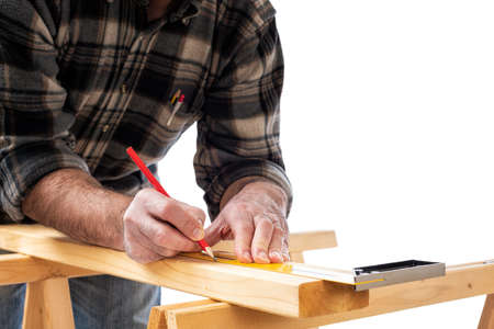 Close-up. Carpenter with pencil and carpenter's square draw the cutting line on a wooden board. Construction industry. White background.の写真素材