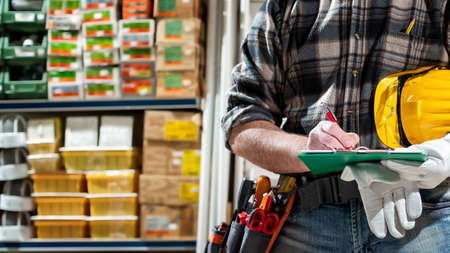 Electrician in the electrical components store writes on the notebook. Construction industry, electrical system.の写真素材