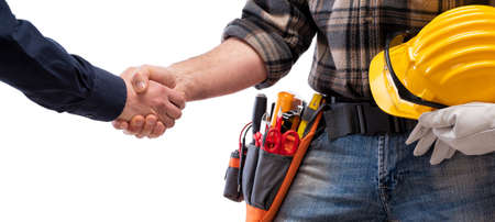 Close-up of a handshake of the electrician carpenter holding helmet and protective goggles in hand. Construction industry, electrical system. Isolated on a white background.の写真素材