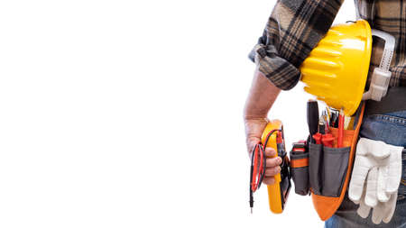 View from behind, electrician holds multimeter tester in hand, helmet with protective goggles. Construction industry, electrical system. Isolated on a white background.の写真素材