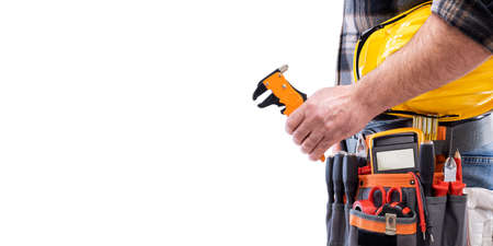 Electrician holds wire stripper plier in hand, helmet with protective goggles. Construction industry, electrical system. Isolated on a white background.の写真素材