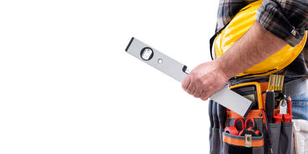 Electrician holds the level in his hand, helmet with protective goggles. Construction industry, electrical system. Isolated on a white background.の写真素材