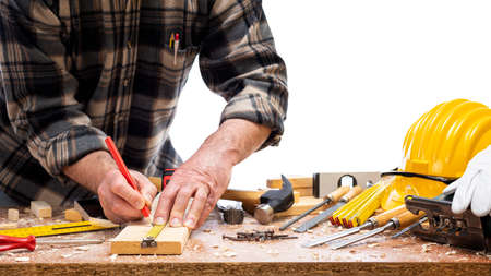 Close-up. Carpenter with pencil and the meter marks the measurement on a wooden board. Construction industry. Isolated on a white background.の写真素材