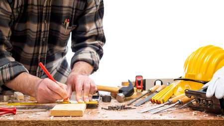 Close-up. Carpenter with pencil and carpenter's square draw the cutting line on a wooden board. Construction industry. Isolated on a white background.の写真素材