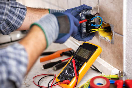 Electrician at work with screwdriver fixes the cable in the sockets of a residential electrical...
