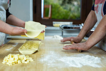 Close-up of woman's hands working the dough to prepare cheese ravioli. Traditional Sardinian cuisine.の写真素材