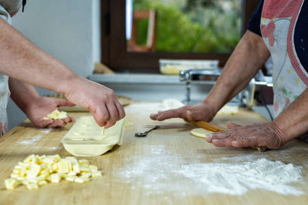 Close-up of woman's hands working the dough to prepare cheese ravioli. Traditional Sardinian cuisine.の写真素材