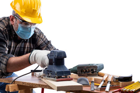 Carpenter worker at work isolated on white background, wears helmet, goggles, leather gloves and surgical mask to prevent  infection.の写真素材