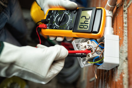 View from above. Electrician worker at work with the tester measures the voltage in a switch of a residential electrical system. Working safely with protective gloves. Construction industry.の写真素材