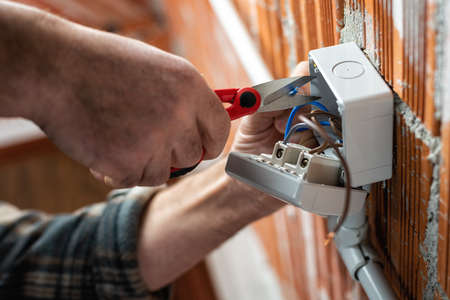 Bottom view. Electrician worker at work with scissors prepares the electrical cables of an electrical system. Construction industry.の写真素材