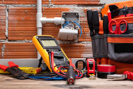 Tool bag, tools and work equipment for electrician technician on a wooden workbench. Construction industry.の写真素材