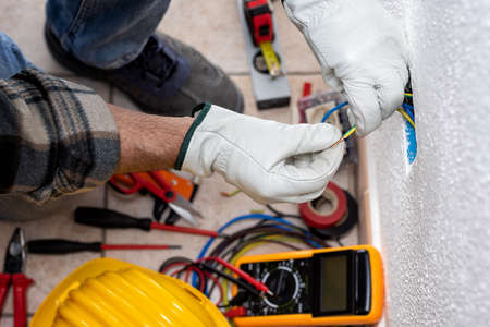 View from top. Electrician worker at work prepares the electrical cables of an electrical system. Working safely with protective gloves. Construction industry.の写真素材