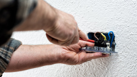 Electrician worker with screwdriver fixes electrical cables in the terminals of the socket of an electrical system. Construction industry.の写真素材