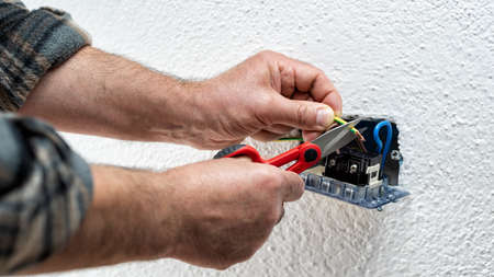 Electrician worker at work with scissors prepares the electrical cables of an electrical system. Construction industry.の写真素材