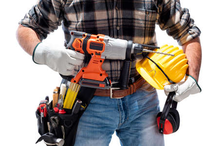 Carpenter worker at work holding the rechargeable hammer drill and safety equipment, isolated on white background. Construction industry. Carpentry.の写真素材