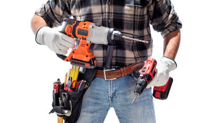 Carpenter worker at work holding the rechargeable hammer drill and the rechargeable screwdriver, isolated on white background. Construction industry. Carpentry.の写真素材