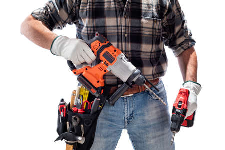Carpenter worker at work holding the rechargeable hammer drill and the rechargeable screwdriver, isolated on white background. Construction industry. Carpentry.の写真素材