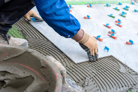 Bricklayer tiler places tiles of a new floor on the glue. Construction industry. Building.の写真素材