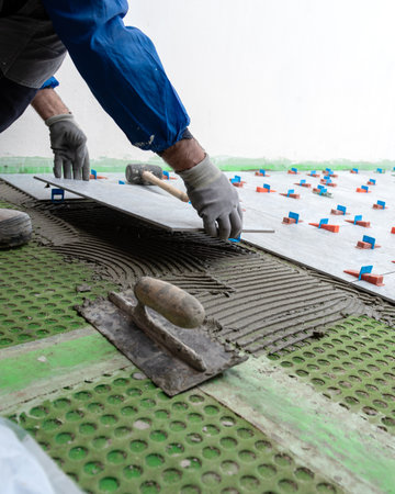 Bricklayer tiler places tiles for a new floor on cement glue. Construction industry. Building.の写真素材