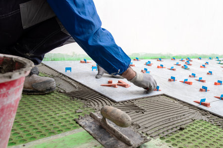 Bricklayer tiler installs tiles using leveling spacers. Construction industry. Building.の写真素材