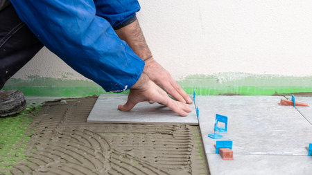 Bricklayer tiler installs tiles using leveling spacers. Construction industry. Building.