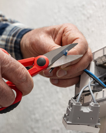 Electrician worker at work with scissors prepares the electrical cables of an electrical system....