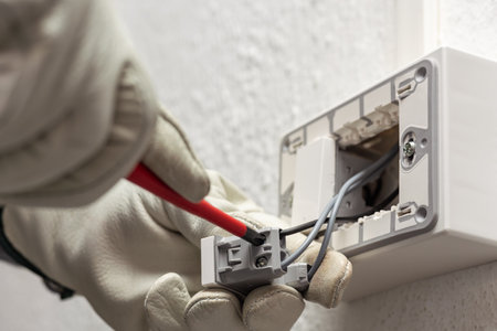 Electrician worker with screwdriver fixes electrical wires in the terminals of the diverter switch of an electrical system. Working safely with protective gloves. Construction industry.の写真素材