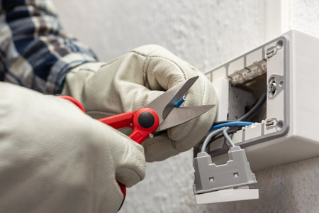 Electrician worker at work with scissors prepares the electrical cables of an electrical system. Working safely with protective gloves. Construction industry.の写真素材