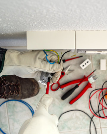 Electrician worker with screwdriver fixes electrical wires in the terminals of the socket of an electrical system. Working safely with protective gloves. Construction industry.の写真素材