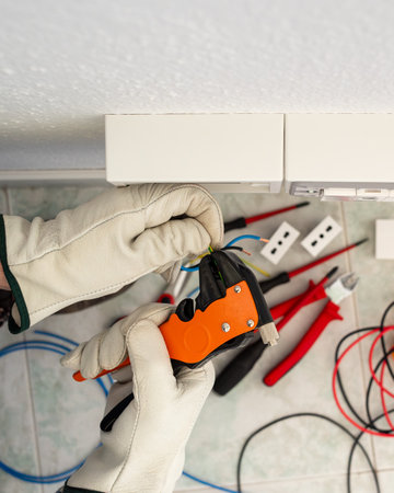 Electrician worker at work with wire stripper pliers prepares the electrical cables of an electrical system. Working safely with protective gloves. Construction industry.の写真素材