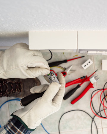 Electrician worker at work with wire stripper pliers prepares the electrical cables of an electrical system. Working safely with protective gloves. Construction industry.の写真素材
