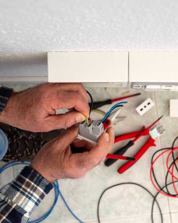 Electrician worker inserts electrical cables into the socket terminals of an electrical system. Construction industry.の写真素材