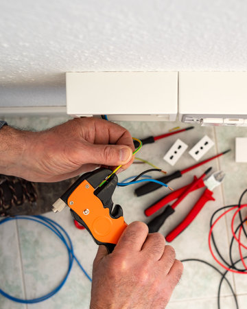 Electrician worker at work with wire stripper pliers prepares the electrical cables of an electrical system. Construction industry.の写真素材