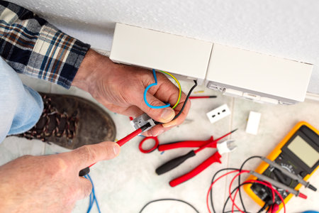 Electrician worker with screwdriver fixes electrical wires in the terminals of the socket of an electrical system. Construction industry.の写真素材