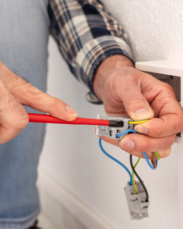 Electrician worker with screwdriver fixes electrical wires in the terminals of the socket of an electrical system. Construction industry.の写真素材