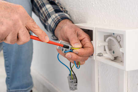 Electrician worker with screwdriver fixes electrical wires in the terminals of the socket of an electrical system. Construction industry.の写真素材