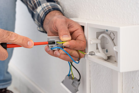 Electrician worker with screwdriver fixes electrical wires in the terminals of the socket of an electrical system. Construction industry.の写真素材