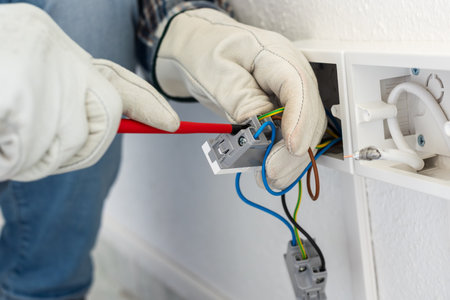Electrician worker with screwdriver fixes electrical wires in the terminals of the socket of an...