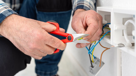 Electrician worker at work with scissors prepares the electrical cables of an electrical system. Construction industry.の写真素材