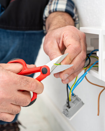 Electrician worker at work with scissors prepares the electrical cables of an electrical system. Construction industry.の写真素材