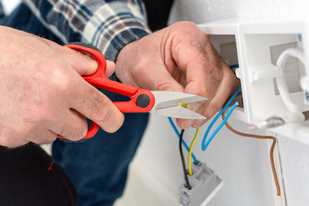 Electrician worker at work with scissors prepares the electrical cables of an electrical system. Construction industry.の写真素材