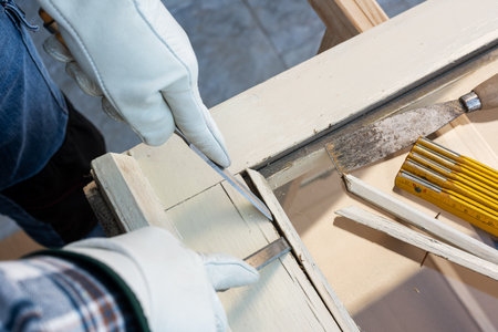 Carpenter using chisels removes the wooden frame blocking the glass from an old wooden window. Construction industry, carpentry. Restoration.の写真素材
