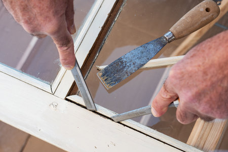 Carpenter using chisels removes the wooden frame blocking the glass from an old wooden window. Construction industry, carpentry. Restoration.の写真素材
