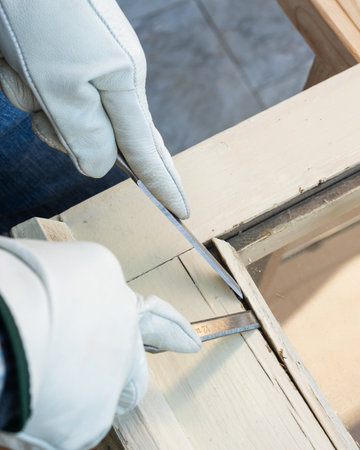 Carpenter using chisels removes the wooden frame blocking the glass from an old wooden window. Construction industry, carpentry. Restoration.の写真素材