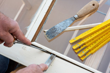 Carpenter using chisels removes the wooden frame blocking the glass from an old wooden window. Construction industry, carpentry. Restoration.の写真素材