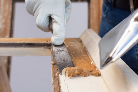 Carpenter using heat gun and wood scraper removes paint from old wooden window. Construction industry, carpentry. Restoration.の写真素材