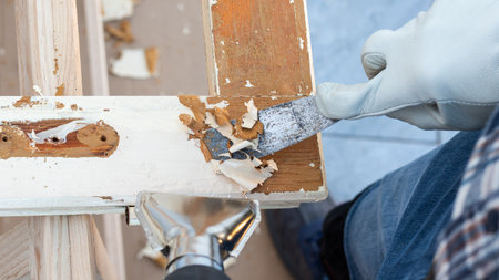 Carpenter using heat gun and wood scraper removes paint from old wooden window. Construction industry, carpentry. Restoration.の写真素材