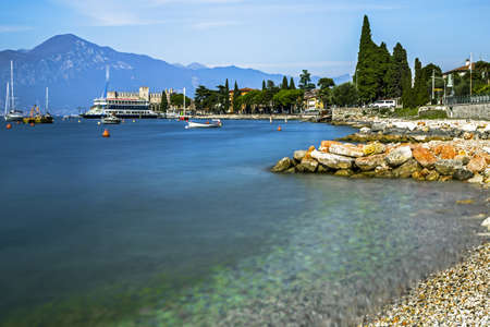 Scenic long exposure view of a bay and a touristic boat at harbor on Garda Lake, Malcesine, Verona, Italyの写真素材